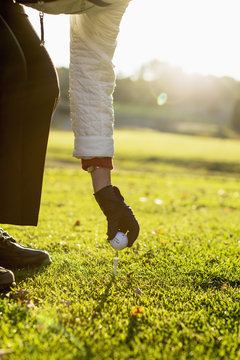 Cropped image of senior woman placing golf ball on tee