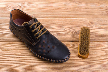 Men's shoe from leather and shoe brush on the wooden background 