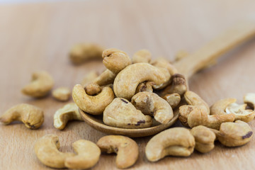 Cashew nuts in wooden spoon on wooden table