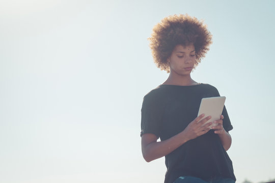 Woman at backlight looking at digital tablet