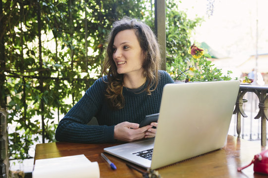 Young woman sitting on balcony using laptop