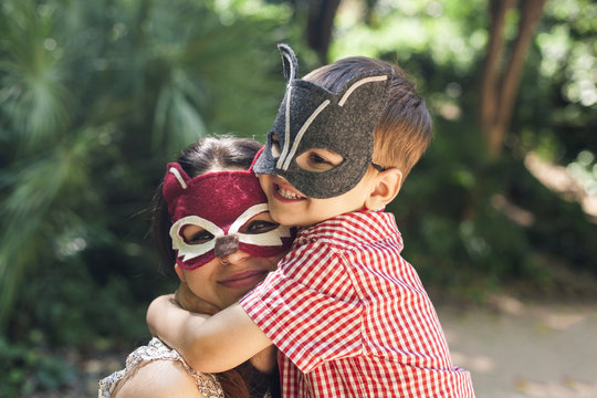 Mother and little son with animal masks playing in the park