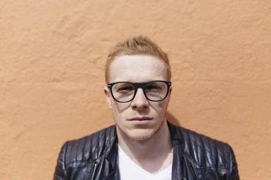 Portrait of strawberry blonde young man wearing black glasses