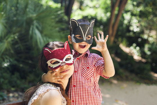 Mother and little son with animal masks playing in the park