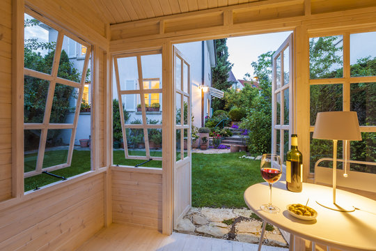 Red wine glass and bottle and bowl of olives on table in a garden shed