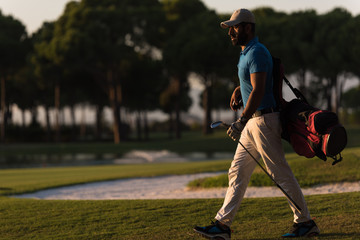 golfer  walking and carrying golf  bag at beautiful sunset