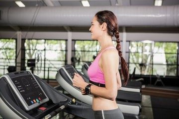 Obraz na płótnie Canvas Woman using smart watch on treadmill