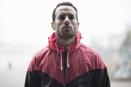 Sporty man in jacket listening to music through headphones