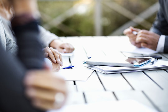 Cropped image of business people with documents and digital tablet at table