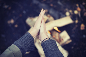 Cropped image of woman rubbing hands over campfire