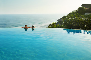Romantic Vacation For Couple In Love. Happy People Relaxing In Infinity Edge Swimming Pool Water,...