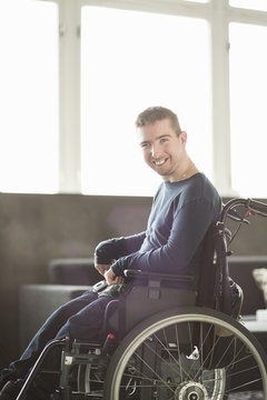Portrait of happy disabled businessman sitting on motorized wheelchair in office