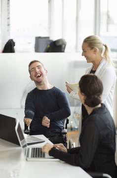 Happy disabled businessman discussing with female colleagues in office