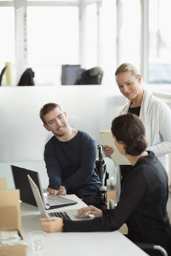 Disabled businessman discussing with female colleagues in office
