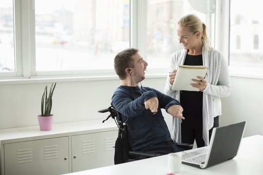 Disabled businessman discussing work with colleague in office