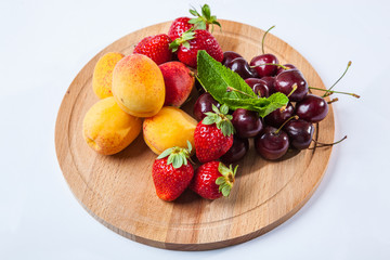 fruits and berries on a wooden cutting board