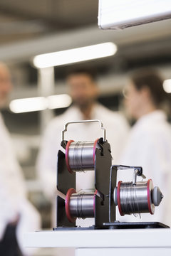 Spools of wire with engineers in background at manufacturing industry