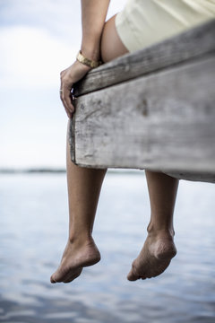 Low Section Of Woman Dangling Feet From Pier