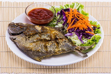 Fried fish with garlic on white plate