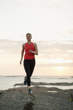 Full length of woman running on rocks at seaside