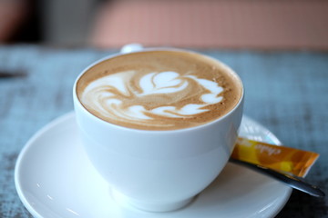 Cup of cappuccino on the wooden table. Close up.