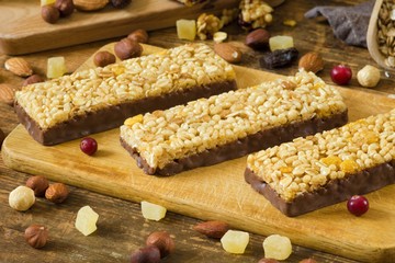 Energy granola bars with cornflakes, puffed cereals and rolled oats covered in chocolate on wooden...
