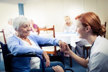 Nurse interacting with a senior woman in wheelchair  - obrazy, fototapety, plakaty