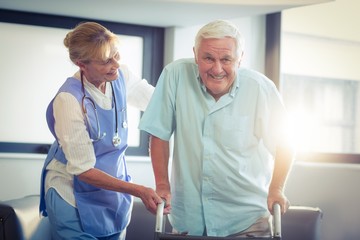 Obraz premium Female doctor helping senior man to walk with walker