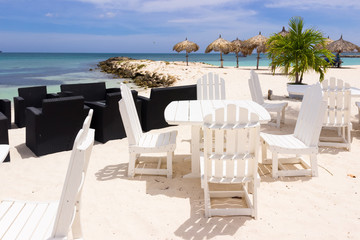 white restaurant tables and chairs on the beach