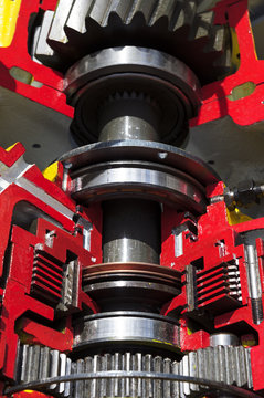 Bulldozer drive gear mechanism cross section, sprockets, bearings, bolts of diesel engine, large construction machine with red and yellow paint coating, heavy industry, detail 