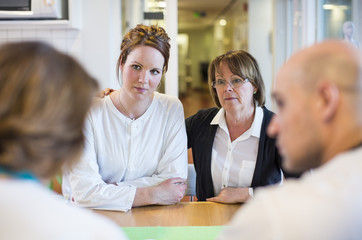 Mother and daughter getting notice from doctors at table in clinic