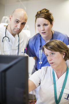 Male and female doctors using Desktop PC together in hospital