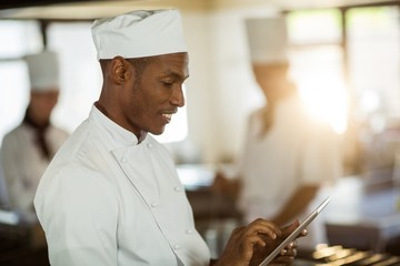 Fototapeta na wymiar Smiling chef using digital tablet