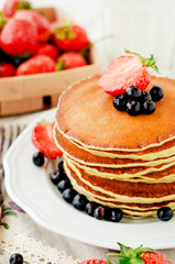 
easy hearty and healthy breakfast , American pancakes with berries , blueberries and strawberries with milk on a wooden background