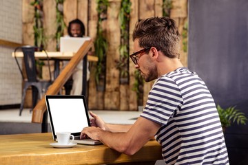Portrait of young man sitting at table using laptop 