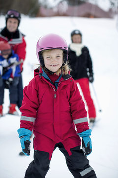 Portrait of girl in ski-wear with family in background