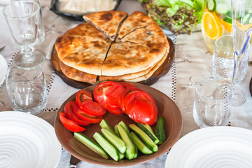 plates, sliced vegetables, pie on served table