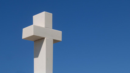 weisses Steinkreuz vor blauem Himmel