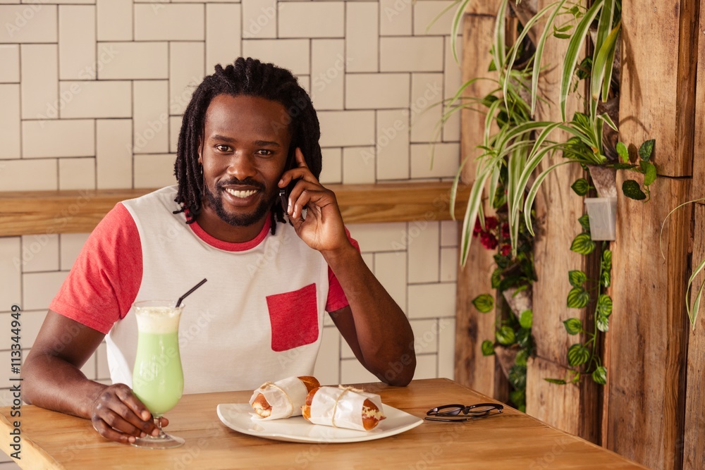 Poster Hipster man smiling at camera while calling with smartphone