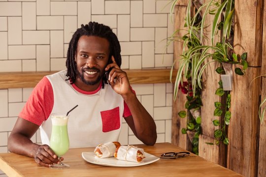 Hipster man smiling at camera while calling with smartphone