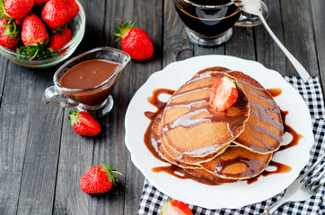 
easy hearty and healthy breakfast , American pancakes with strawberries and chocolate with coffee on a wooden background