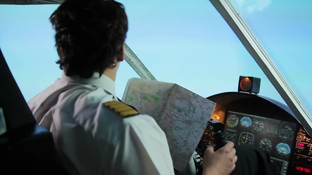 Unreliable airline pilot wearing captain uniform lost direction, checking map