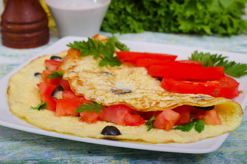 Breakfast, tasty omelet omelette scrambled eggs with tomato, olives and parsley. On a wooden background