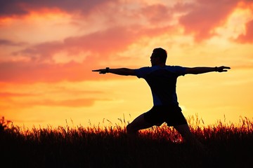 Man is practicing yoga during sunset