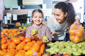 Mother and little girl choosing fresh fruits
