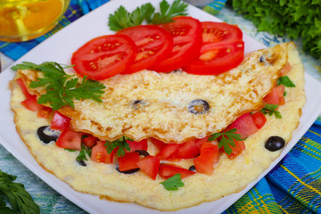 Breakfast, tasty omelet omelette scrambled eggs with tomato, olives and parsley. On a wooden background