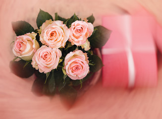 Vase with roses and gift with ribbon