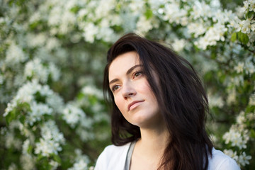 Naklejka premium Young beautiful brunette woman in blooming apple tree garden