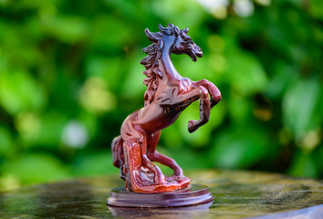 Sculpture of horse made of wood with blurred nature background.