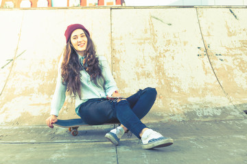 Hipster skateboarder girl with skateboard outdoor at skatepark